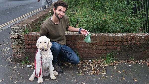 Will Aczel with dog, Ayla, holds up some rubbish by a former bin site on Old Tiverton Rd, Exeter.