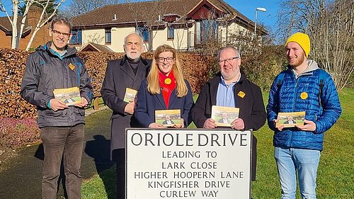 Five Exeter Lib Dems hold canvassing cards in front of a road sign for Oriole Drive